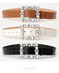 Detailed view of three women's belts with sparkling rhinestone square buckles in black and brown