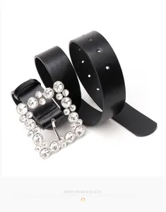 Close-up of a black leather belt featuring a large square buckle encrusted with clear crystals