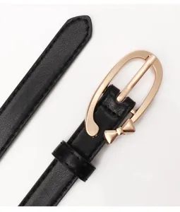 Detail of black leather belt featuring a golden metal bow buckle on white background