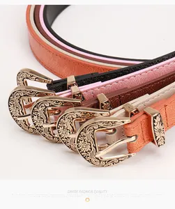 Détail de boucles dorées gravées de fleurs sur des ceintures fines en cuir coloré