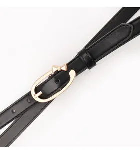 Close-up of a slim black leather belt featuring a golden bow-shaped metal buckle