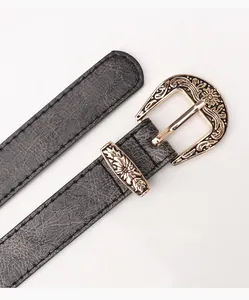 Détail de la boucle dorée sculptée et texture cuir noir sur une ceinture rétro femme