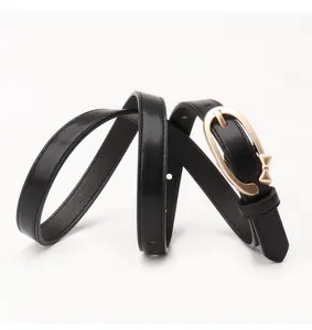 Detail of slim black PU leather belt with gold oval buckle and small bow decoration