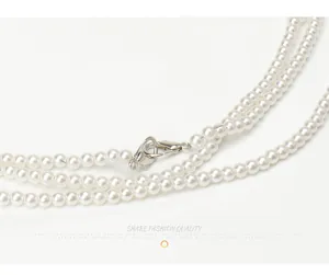 Detailed macro view of white layered pearl necklace with silver lobster clasp and smooth texture