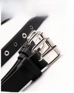 Détail d'une ceinture en cuir noir avec boucle à double ardillon argentée et œillets