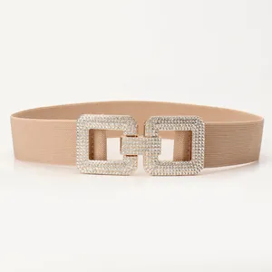 Elastic beige waist belt featuring interlocking square buckles with shimmering rhinestones