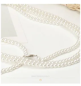 Detailed close-up of glossy pearl necklace layers with elegant silver lobster clasp