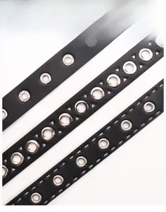 Détail de ceintures en cuir noir avec plusieurs rangées d'œillets métalliques argentés