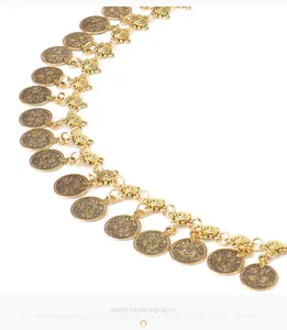 Macro detail of golden metal coin charms and link chain on a bohemian style belt