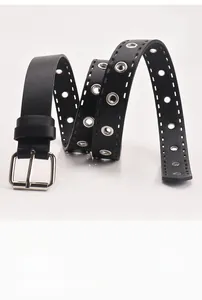 Détail de la ceinture en cuir noir avec double rangée d'oeillets argentés et boucle carrée