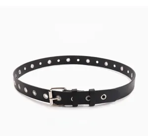 Détail d'une ceinture noire en similicuir avec œillets métalliques et boucle ronde