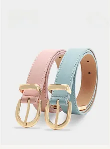 Detailed view of pink and blue leather belts with gold horseshoe buckles and white stitching