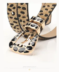 Detailed close-up of a leopard print belt with a gold buckle and black enamel accents