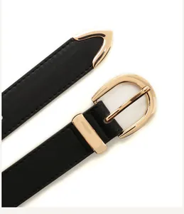 Detail of minimalist black leather belt featuring gold D-ring buckle and metal tip trim