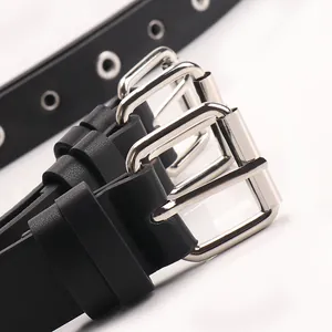 Ceinture punk noire avec boucle en métal argenté et œillets métalliques sur fond blanc