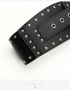 Close-up of black leather wide belt featuring silver punk studs and metal eyelets