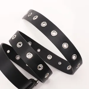 Ceinture en cuir noir tendance avec œillets argentés et strass sur fond blanc immaculé