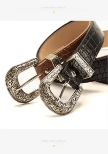 Detail of vintage carved metal buckle and crocodile pattern leather belt for jeans