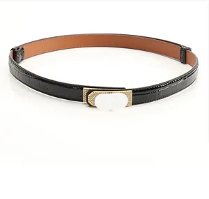 Vue détaillée de la boucle dorée avec strass sur ceinture noire en cuir embossé croco