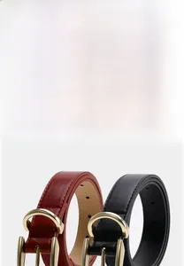 Dettagli di cinture in pelle bordeaux e nera con fibbie in metallo dorato a forma di D