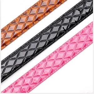 Close-up of diamond lattice embossed patent leather belts in brown black and pink