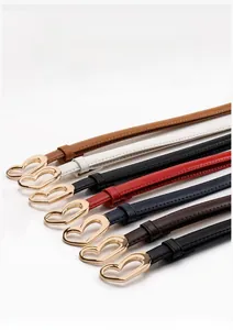 Gros plan de fines ceintures en cuir avec boucles dorées en forme de cœur en diverses couleurs