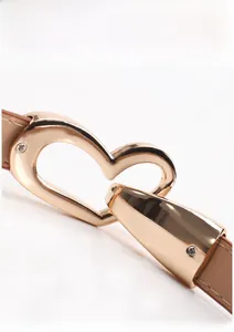 Gros plan sur la boucle de ceinture dorée en forme de cœur avec cuir marron réglable