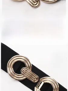 Detail view of interlocking gold concentric circle buckle on black elastic waist belt