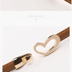 Détail d'une ceinture en cuir marron avec une boucle en forme de cœur doré clair et crochet