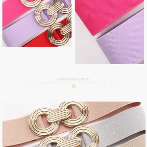 Detail of colorful elastic waist belts with shiny interlocking gold geometric buckles