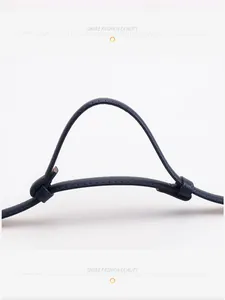 Détail d'une ceinture en cuir bleu foncé ajustable montrant les coutures et le passant noué