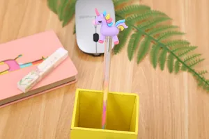 Close-up of a creative unicorn gel pen with a purple topper in a yellow wooden holder