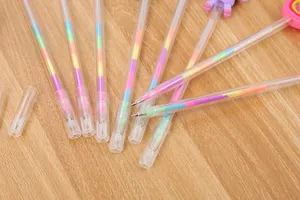 Detail of colorful rainbow gel pens with cute cartoon toppers on a wooden desk surface