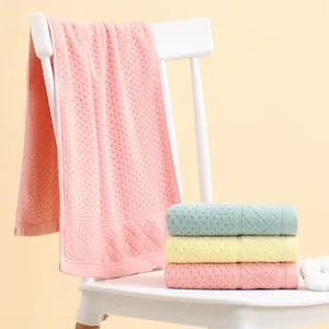 Detail of waffle weave cotton face towels in pink, blue and yellow on white chair