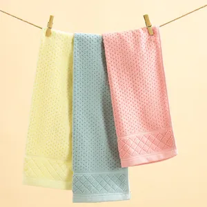 Three-piece cotton towel set in yellow, blue, and pink with honeycomb texture and satin borders