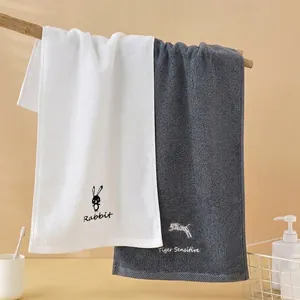 Detail von hängenden Baumwollhandtüchern mit Hasen- und Tigerstickerei am Holzregal