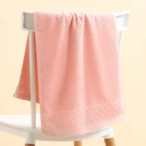 Detail of pink cotton towel with textured weave and diamond embroidery on a chair