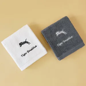 Detailed embroidery of a jumping tiger and text on soft white and gray cotton towels