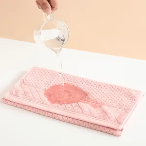 Pink absorbent cotton towel with waffle texture showing superior water absorption