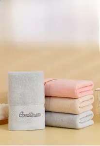 Detail of embroidered 'Goodliness' text on soft cotton towel with plush loop texture