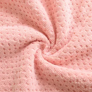 Close-up of pink cotton waffle weave towel showing soft fiber texture and water absorption