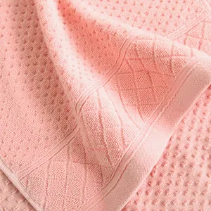 Close-up of pink cotton towel featuring embossed dot patterns and diamond lattice border