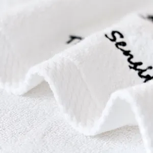 Detailed close-up of soft white Xinjiang cotton towel with black Sensit embroidery