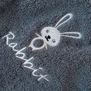 Close-up of deep gray cotton towel featuring delicate white rabbit embroidery and soft loops