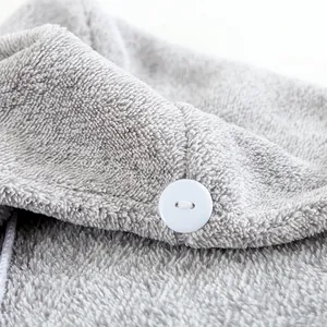 Dettaglio del turbante per capelli in pile corallo grigio con bottone bianco e asola elastica