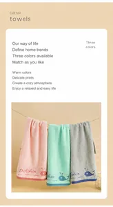 Close-up of cotton towels with dolphin embroidery hanging on a rope in three soft colors