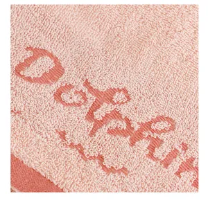 Gros plan d'une serviette en coton rose avec texture jacquard douce et détail tissé