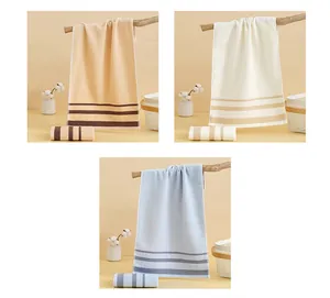 Gros plan de trois serviettes en coton absorbant en beige et bleu avec détails de rayures