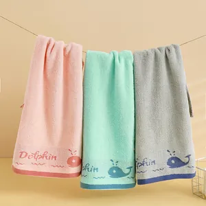 Trois serviettes en coton de couleur rose, vert et gris avec broderie dauphin sur une corde