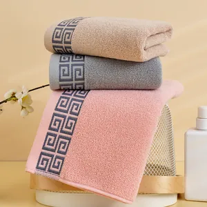 Three-piece set of thick cotton towels in beige, grey, and pink with geometric borders